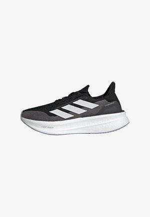 Black athletic shoes with a textured upper, featuring three large white stripes and a thick white sole, labeled "LIGHT BOOST" on the side.