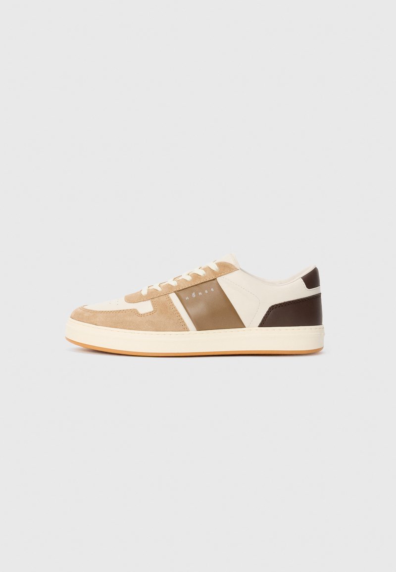 Sneaker de tip low-top cu vârful din suede bej, țesătură crem, panou lateral din piele maro, șireturi albe și talpă din cauciuc deschis, pe fundal alb.