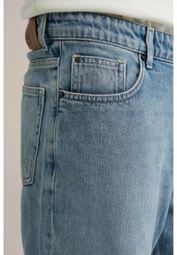 Lichtblauwe denimjeans met een klassiek ontwerp, voorzien van een frontzak, achterzak en details in koperkleurige hardware.