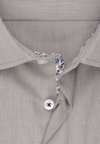 Ljusbrun rutig skjorta med krage, featuring vita knappar och ett blommönster på insidan av kragen. Strukturerad tyg.