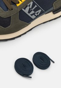 Scarpa sportiva in suede verde scuro e rete blu navy con dettagli gialli e logo grigio, accompagnata da due lacci rotondi blu scuro.
