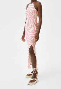 Rosa Zebra-Print Midi-Kleid mit seitlichem Schlitz und Raffung, aus leichtem Stoff hergestellt. Kombiniert mit beigen Plateau-Sandalen mit Knöchelbindungen.