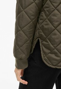 Olivno zelena prešita jakna z diamanti vzorcem, rebrastimi manšetami in razporkom na spodnjem robu. Sijajen, gladek material z udobnim krojem.