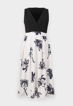 Ärmlös klänning med en svart, V-ringad livdel och en vit kjol med marinblå blommönster. Tyget är slätt med plisserade detaljer.