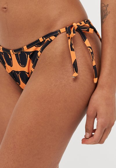 Orange bikini bottom featuring a black pattern, adjustable side ties, and a smooth texture. Designed for a fitted, minimal coverage style.