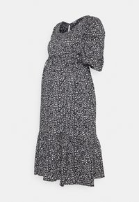 Vestido de maternidade com um padrão abstrato em preto e branco, com mangas bufantes, barra com babados e corpete elástico para maior conforto.