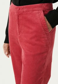 Rode corduroy broek met een ribbeltextuur, voorzien van zijzakken en een getailleerde pasvorm. De tailleband heeft een soepele afwerking.