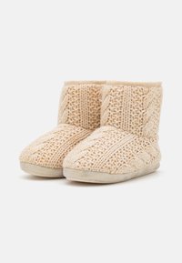 Beige gebreide enkellaarsjeslippers met een gestructureerd patroon. Heeft een gevoerde zool en een zachte, warme binnenvoering.