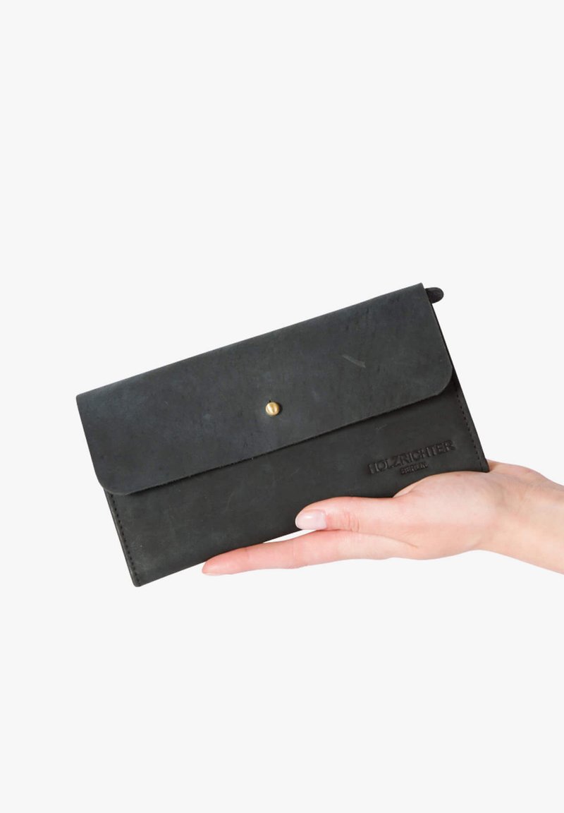 Black leather wallet with a flap and snap closure, featuring embossed branding. Smooth texture and rectangular shape, held in a hand.
