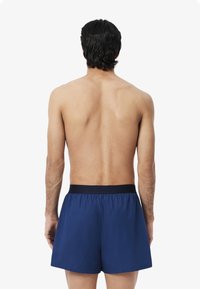 Navy blue swim shorts with an elastic waistband, crafted from lightweight fabric, featuring a simple design without patterns or accents.