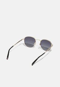 Gold metal sunglasses with dark gray lenses. Slim black arms with a slight curve and colored accents at the tips. Angular lens shape.