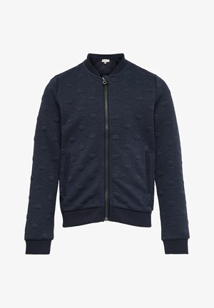 Marineblå bomberjakke med lynlås og tekstureret polkaprikket mønster, ribstrikkede ærmeafslutninger, krave og kant forneden, med to sidelommer.
