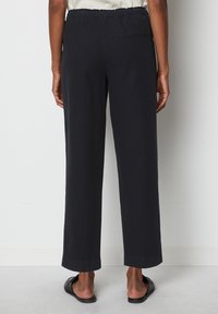 Black wide-leg pants with an elastic waistband and a back pocket. Smooth, lightweight fabric with a straight cut and turned-up cuffs.