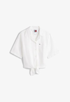 Biała koszula z krótkim rękawem z wiązanym przodem, posiadająca wycięty kołnierzyk i jedną kieszeń na piersi. Wykonana z lekkiej tkaniny.