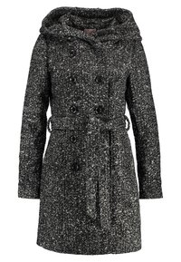 Svart och vit texturerad kappa med dubbelknäppt design, stor huva och ett tygbälte. Har synliga knappar och fickor.