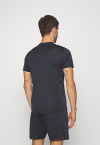 Svart träningströja med kort ärm och rund hals, tillverkad av ett slätt, lätt material, tillsammans med matchande shorts. Inga synliga mönster eller logotyper.