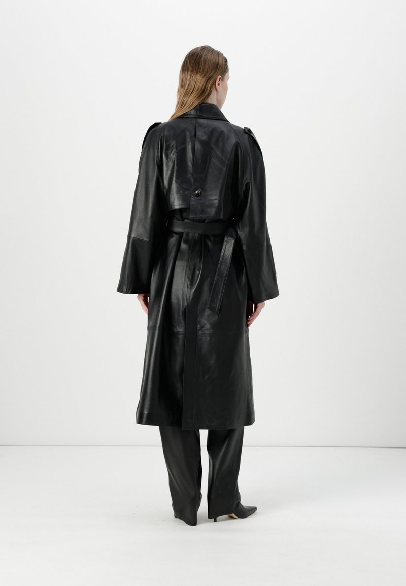 Schwarzer Leder-Trenchcoat mit einem taillierten Gürtel, weiten Ärmeln und einer Knopfdetail auf der Rückseite. Glatte Textur, knielanges Design.