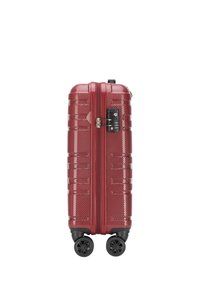 Valise rigide rouge avec une surface texturée, deux zips, serrure intégrée et quatre roues noires pivotantes pour la mobilité.