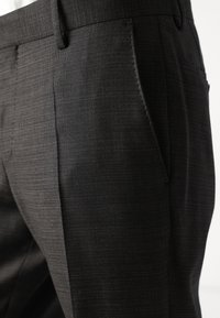 Skræddersyede sorte bukser lavet af struktureret stof. Har sidelommer og et slim fit design. Diskret pinstribet mønster synligt.