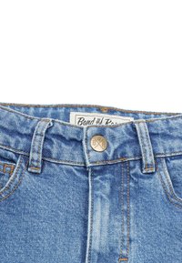 Ljusblå denimjeans med knappstängning, framfickor och synliga sömmar. Etiketten inuti läser "Band & R."