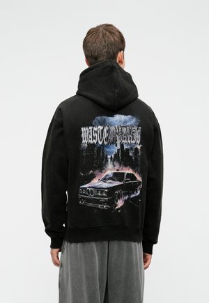 Crna dukserica s kapuljačom i grafičkim dizajnom koji prikazuje automobil i urbani horizont. Opustitog kroja, s rebrastim manžetama i rubom.