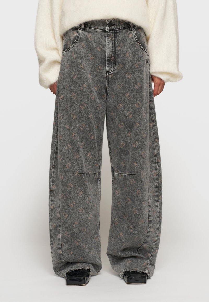 Jeans de pierna ancha en denim gris deslavado, con un sutil patrón floral en marrón claro, de talle alto y con detalles de dobladillo desgastado.