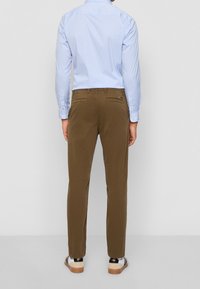 Ljust blå randig skjorta, bruna chinos, avslappnad passform, två bakfickor, kombinerad med casual skor med en tan-färgad sula och svarta accenter.