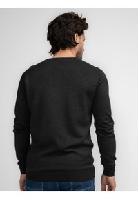 Donkergrijze trui met een ronde hals, lange mouwen en geribbelde manchetten. Gemaakt van zachte stof, met een gladde textuur en minimale ontwerpdetails.
