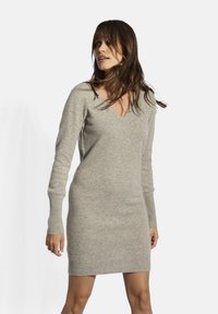 Abito grigio a maglia con scollatura a V, maniche lunghe e polsini e orlo a coste. La texture sembra morbida e leggermente pelosa.