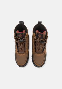 Braune Wanderstiefel aus Mesh und synthetischen Materialien, mit schwarzen Sohlen, Schnürsenkeln und einem roten Futter. Logo auf der Zunge abgebildet.