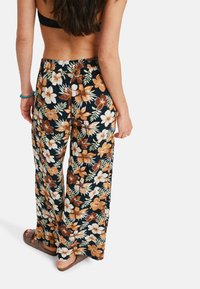 Floral print wide-leg trousers in navy with orange and white flowers. Elastic waistband, lightweight fabric, and relaxed fit. Casual look.