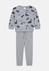 Completo sportivo grigio per bambini composto da una maglietta a maniche lunghe con stampe di dinosauri blu e nere, abbinata a pantaloni jogger con cordino.