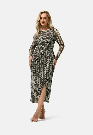 Woman wearing a long-sleeve, patterned midi dress with a twisted waist detail and front slit, paired with beige ankle-strap heels.