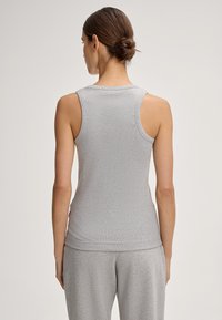 Grijze mouwloze top gemaakt van een zachte, rekbare stof met een ronde hals en een getailleerd design, met een subtiele ribbelstructuur.