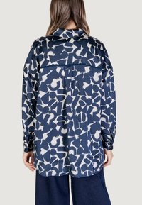 Camicia blu navy con un bold pattern astratto bianco, maniche lunghe e colletto, realizzata in un tessuto morbido con una vestibilità comoda.