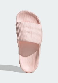 Rosa slide-sandal med ribbad textur, öppen tå-design och en konturerad sula. Tillverkad av flexibelt material med en slät yta.