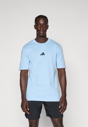 Világoskék pamut póló kerek nyakkivágással, rövid ujjakkal, az elején fekete Adidas logóval. Fekete sorttal viselve.