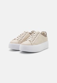 Sneaker in pelle beige con suola piatta bianca spessa, presentano punta rotonda, chiusura con lacci e un accento decorativo in marrone sul tallone.