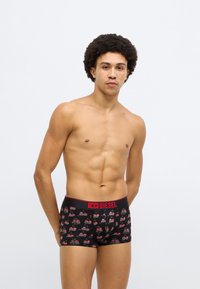 Fekete boxernadrág ismétlődő cseresznye mintával, piros elasztikus derékpánttal, amelyen vastag betűkkel "DIESEL" felirat olvasható.