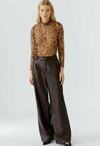Leren blazer met luipaardprint en lange mouwen, met een ruches bij de hals, gecombineerd met high-waisted, wijde bruine leren broek. Glad materiaal, getailleerde pasvorm.