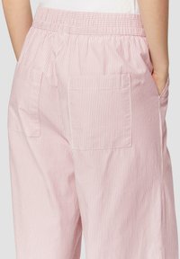 Pantalons à rayures roses avec une ceinture froncée et deux poches arrière. Le tissu est léger avec de fines rayures verticales.