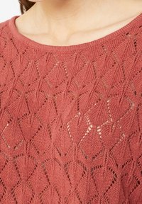 Suéter de punto en color rosa empolvado, con un patrón de encaje que presenta formas de diamante y puntadas abiertas. Escote redondeado y tejido texturizado.