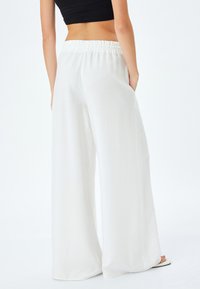 Witte wijde broek met een smocktailband, voorzien van zijzakken en een zachte, lichtgewicht stof die elegant valt.