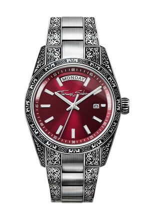 Silver watch with ornate engraved patterns, a red dial, day and date display, and Thomas Sabo logo on the face.