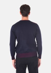 Maglione lavorato a maglia blu navy con colletto rotondo, polsini e orlo a coste. Presenta accenti color bordeaux sulle spalle. Texture liscia, vestibilità slim.
