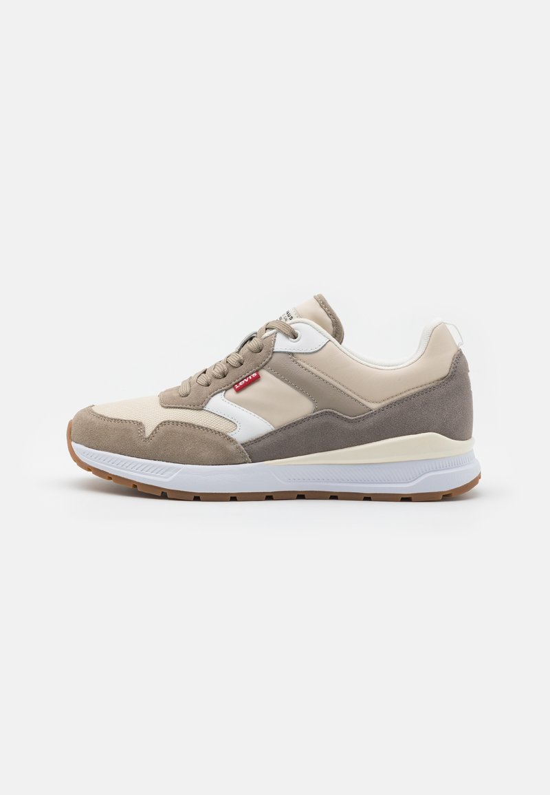 Sneaker beige e grigio con una combinazione di suede e pelle liscia, con dettagli bianchi e suola in gomma. Inclusi lacci e un dettaglio del logo.