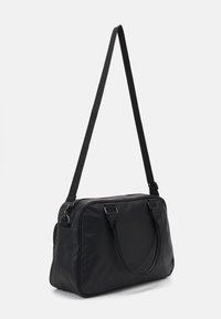 Černá kožená kabelka přes rameno s obdélníkovým tvarem, pevným madlem a nastavitelným popruhem. Hladký povrch a minimalistický design.