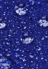 Diepblauwe textuur met waterdruppels. De druppels variëren in grootte en reflecteren licht, wat een glanzend uiterlijk creëert.