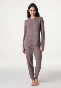Top lungo a maniche con texture marrone e pantaloni abbinati. Il top presenta un colletto rotondo; i pantaloni hanno un fit affusolato alle caviglie.
