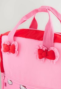 Sac à dos rose avec une finition lisse et mate, orné d'accents rouges et de détails de nœud froncé sur le haut et à l'avant. Fermeture éclair en bas.